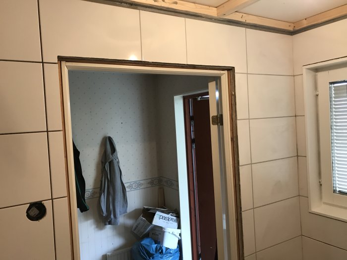 Delvis fogat badrum under renovering med kakelväggar och oavslutat takarbete.