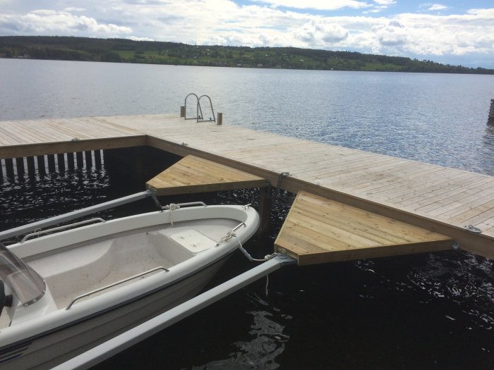 Träplattformar byggda på y-bommar vid en brygga för enklare tillgång till båten på en sjö.