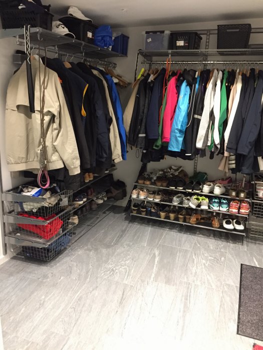 Hallgarderob med hängande kläder och skohyllor fulla av skor, inrett med IKEA elfahyllsystem.