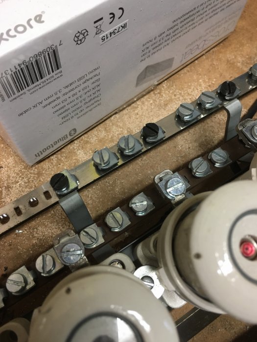 Elektrisk central med skruvsäkringar och metalldon nära kartong.