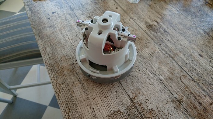 En ny vit elektrisk motor placerad på ett träbord, redo att skruvas ihop och installeras.