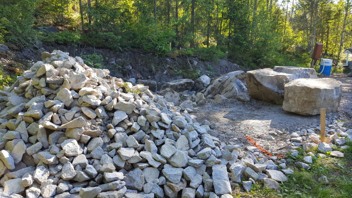 En hög med grus och större bergstycken i en nyligen utgrävd och sprängd terräng.