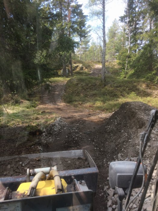 Vy från en traktor som visar nygrusad skogsväg under anläggning.