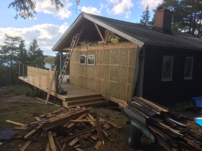 Hus under renovering med nyligen uppsatt gavelspets och utspritt virke framför.