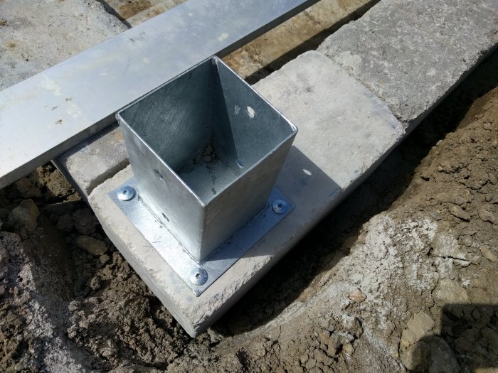 Metallfäste för byggprojekt fastskruvat i betongplatta med synlig Hilti husskruv.