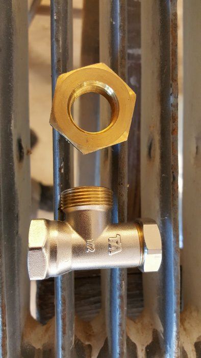 En bussing och en returventil framför en radiator, storlek på gängor matchar ej.