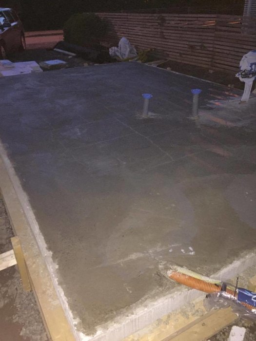 Ny betongplatta med synliga sprickor och golvvärmerör under kvällsljus.