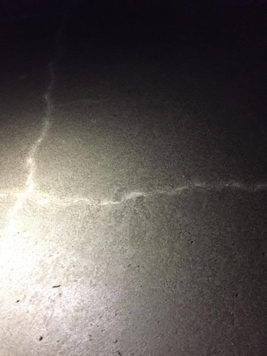 Nylagd betongplatta med synliga sprickor under konstgjort ljus, vilket indikerar skador som kan orsakats av för lite bevattning.