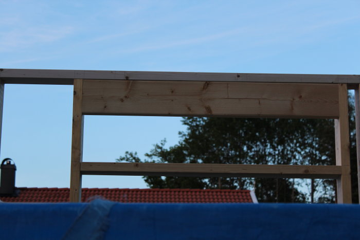 Träregelverk för dörröppning i byggprojekt med synliga reglar och himmel i bakgrunden.