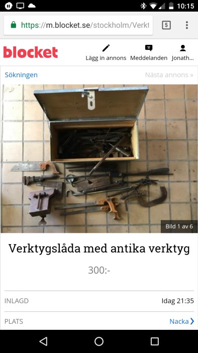 Antik verktygslåda öppen med gamla verktyg på kaklat golv.