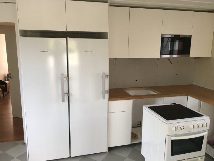 Köksrenovering med nya fullstora kyl och frys, inbyggd mikrovågsugn och spis, lucklös diskmaskin.