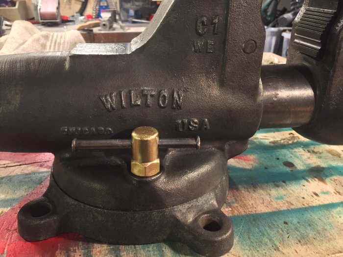 Restaurerat gammalt Wilton-skruvstäd med mässingsdetaljer på en verkstadsbänk.