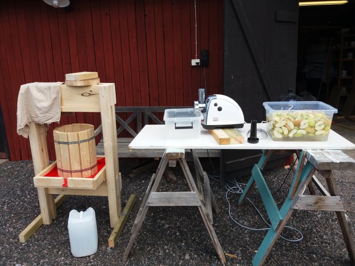 Hemmagjord mustpress och köttkvarn på bord med skivade äpplen redo för mustning.