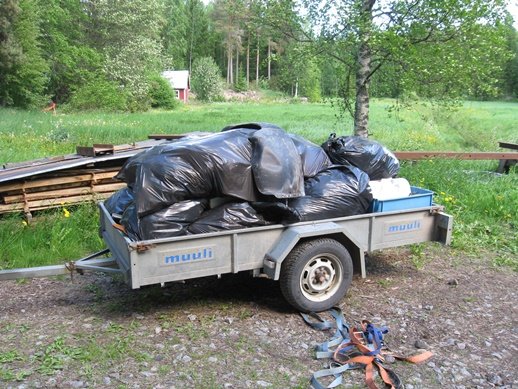 Ett släp fyllt med svarta sopsäckar insamlade från paddelturer redo för sophantering.