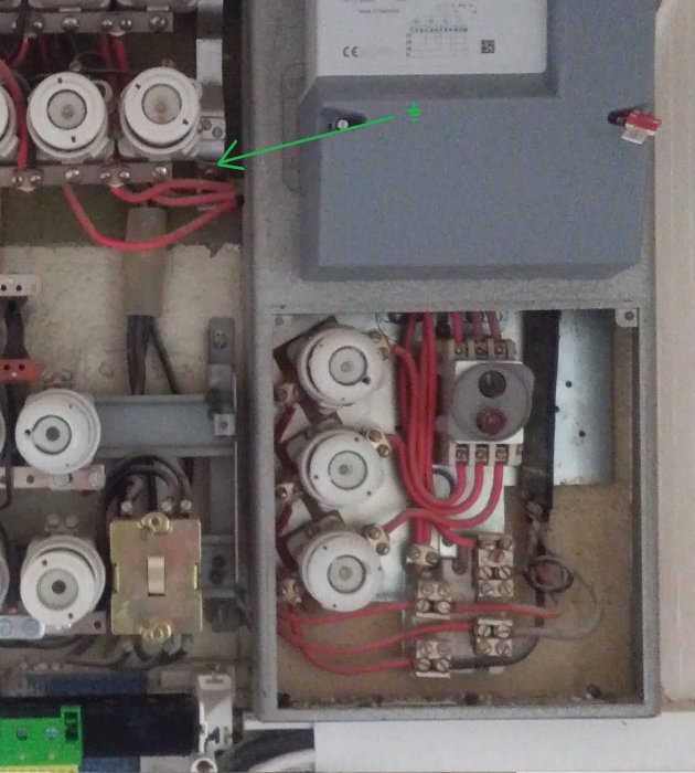 Öppet elskåp med mätare, tre faser, en PEN-ledare och röda kablar, en markerad med grön pil.