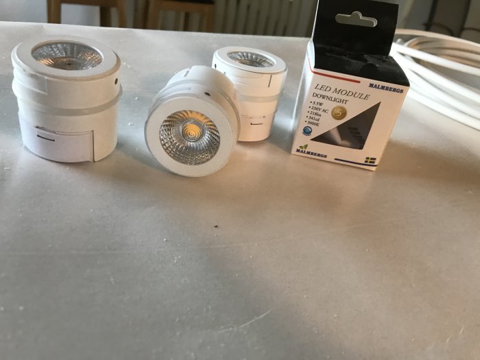 Vita LED-spotlights på ett bord bredvid förpackningen, redo för installation.