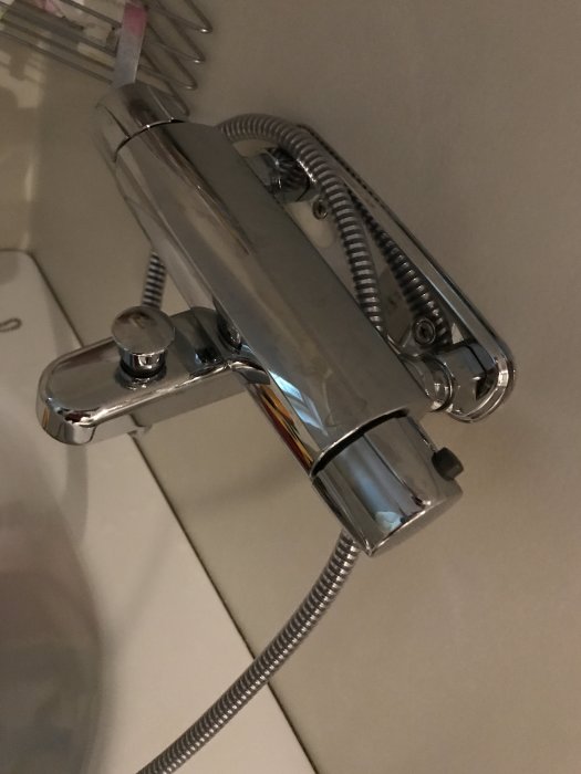 Kromad termostatblandare med duschslang monterad på vägg, i badrumsmiljö.