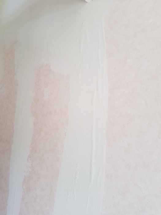 Vägg med lösa tapeter och spackel över områden där tapeten lossnat.