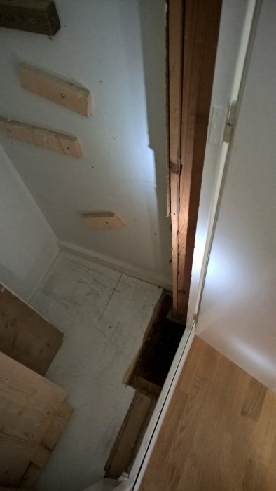 Golv och väggöppning i ett hem under renovering, förberett för installation av stålpelare och balkar.