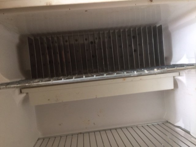 Interiör av ett använt kylskåp med synlig modellnummerplatta.