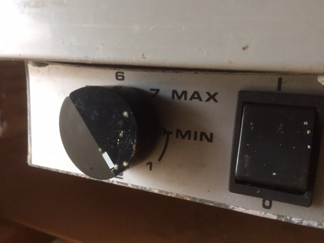 Närbild av en smutsig vred och temperaturkontrollskala på en vit apparat, möjligtvis en del av ett kylskåp.