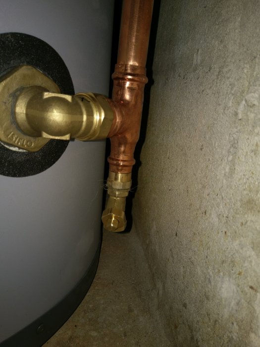 Ventil installerad på kopparledning bakom en tank för att möjliggöra tappning vid behov.