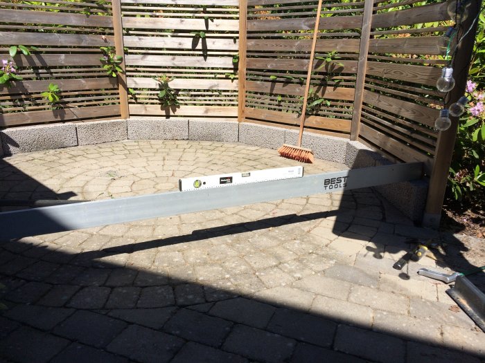 Konstruktion av uteplats med lecablock och verktyg för att rikta upp stolpar.