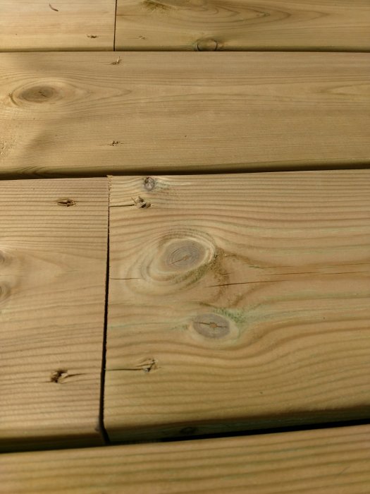 Närbild av ny altan med trätrall som visar små sprickor och skarvar.