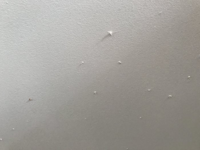 Närbild på ett innertak med knottror och ojämnheter i ytan.