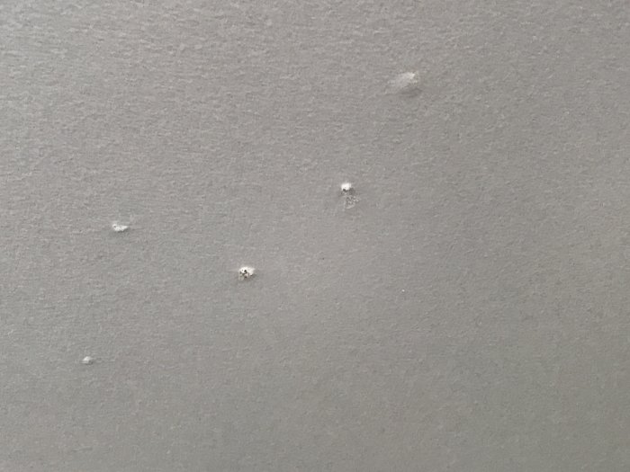 Några upphöjda knottror på en målad takyta som illustrerar problem beskrivna i ett badrums/köksrenoveringsprojekt.