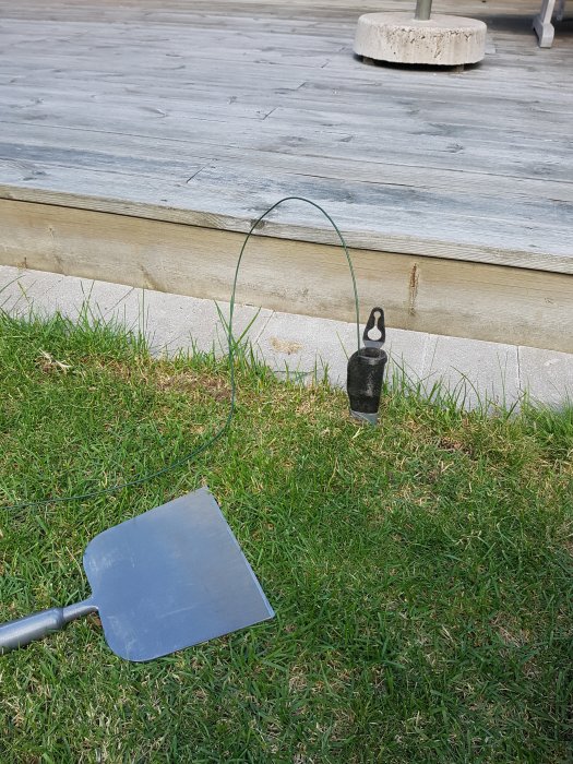 Skrapa på gräsmatta med slipad kant, kabel i slida, bredvid trätrall och stubbe.