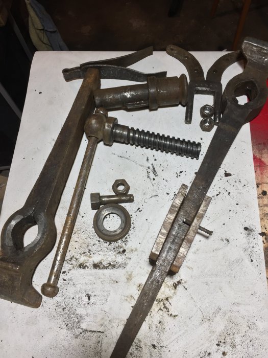 Gammalt skruvstäd och smidesverktyg på ett smutsigt bord efter rengöring och identifiering av märkningar.