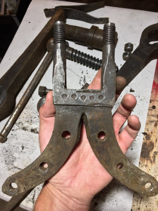 Ett gammalt skruvstäd med tydliga renoverade detaljer och stansmärkningar i en hand, redo för montering.