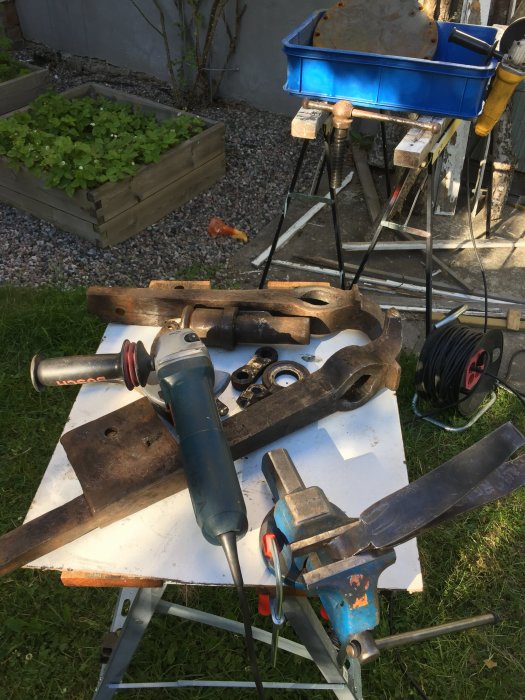 Renoverat skruvstäd och verktyg för smide på arbetsbänk utomhus.