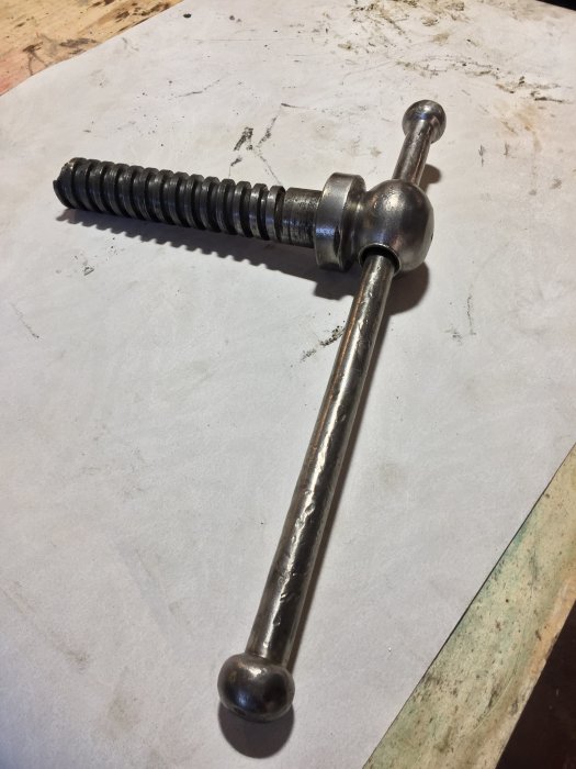 Rengjord skruv från ett gammalt skruvstäd mot en suddig bakgrund, redo för montering och smide.