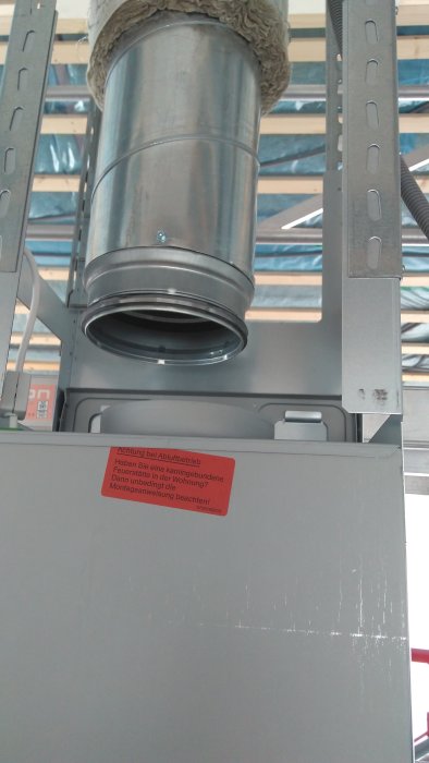 Rör från ventilation ofullständigt anslutet till fläkt, centreringsproblem, isoleringsmaterial syns.