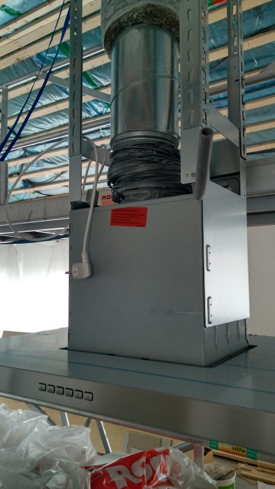 Fläktanordning otestad med otrimmad flexibel ventilationskanal monterad på stålhylla.