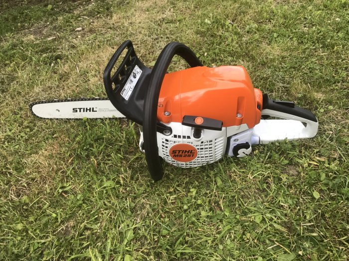 Ny motorsåg av märket Stihl MS 261 ligger på gräsytan.