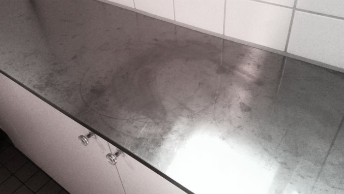 Bänkskiva i badrum med tydliga fläckar och missfärgningar, möjliga skador från rengöringsmedel.