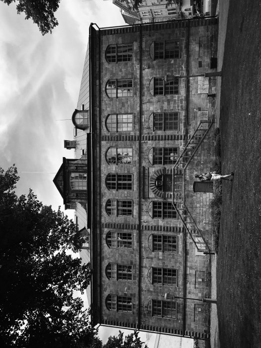 Svartvit bild av en ståtlig byggnad vriden 90 grader med ett noir-filter.