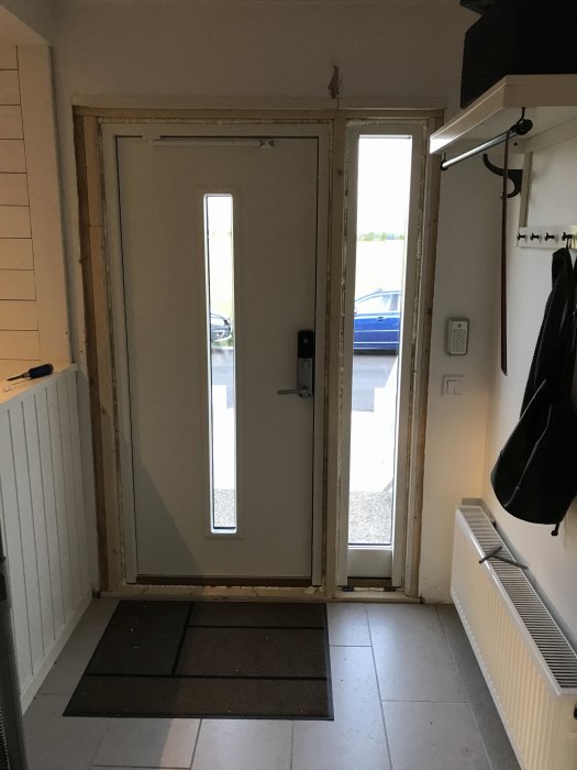 Nyinstallerad entrédörr i ett hus, med synliga nybyggda reglar och karmfäste.