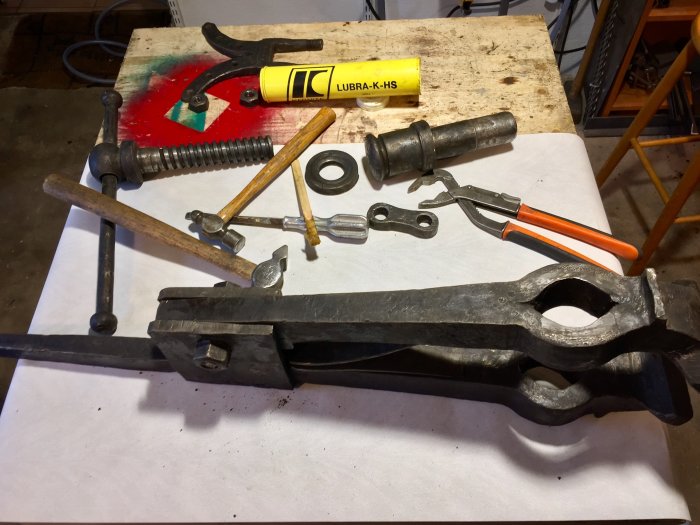 Återmonterade verktyg och smort fjädermekanism på arbetsbänk med oxidsvart finish.