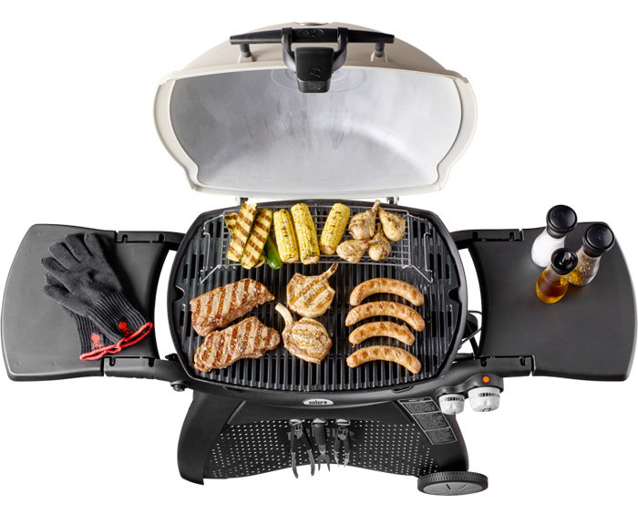 Öppen gasolgrill Weber Q 3200 med grillade majs, kyckling och korv, grillvantar och kryddflaskor på sidohyllorna.