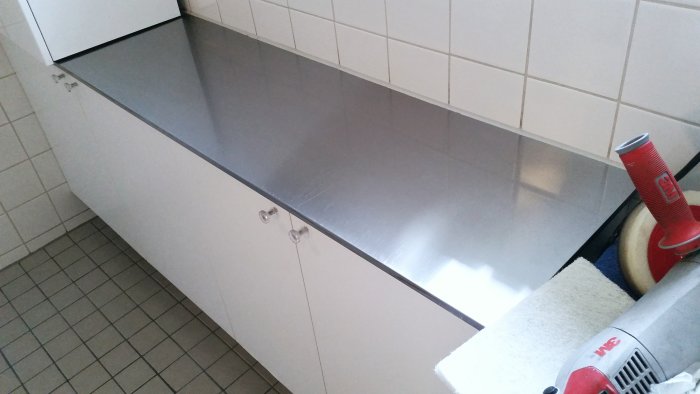 Rengjort och polerat köksbänk i rostfritt stål med slipdukar och polermaskin, utan synliga repor.