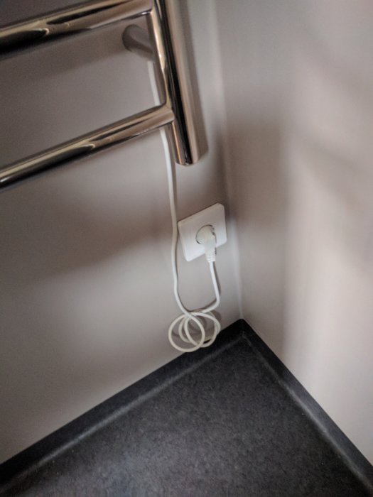 Eluttag nära golv med löst hängande sladd i ett badrum.