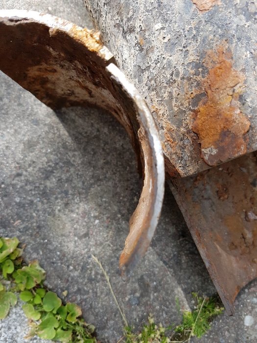 Närbild på ett korroderat gjutjärnsavloppsrör med tunnande gods.