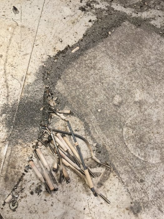 Svetsfogar och olika svetsverktyg utspridda på en smutsig betonggolv efter ett byggprojekt.