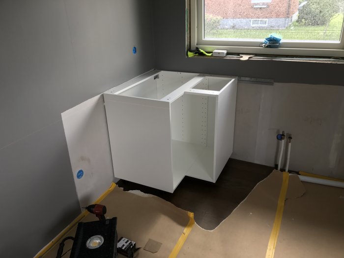 Ikeas köksstomme monterad på väggen under installation, skyddspapp och verktyg på golvet.