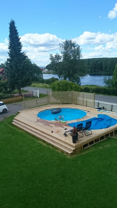 Trädäck under konstruktion med pool, möbler och leksaker, planerad lutande avslutning till vänster.