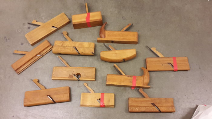 Samling gamla trähyvlar och stämjärn med rött skyddstejp, i olika storlekar och profiler.